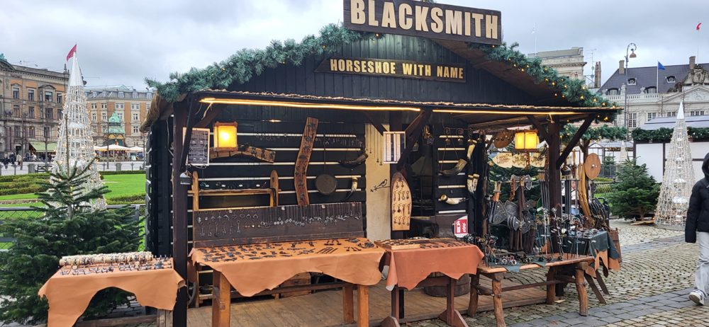 Drewniany domek z napisem Blacksmith na jarmarku bożonarodzeniowym